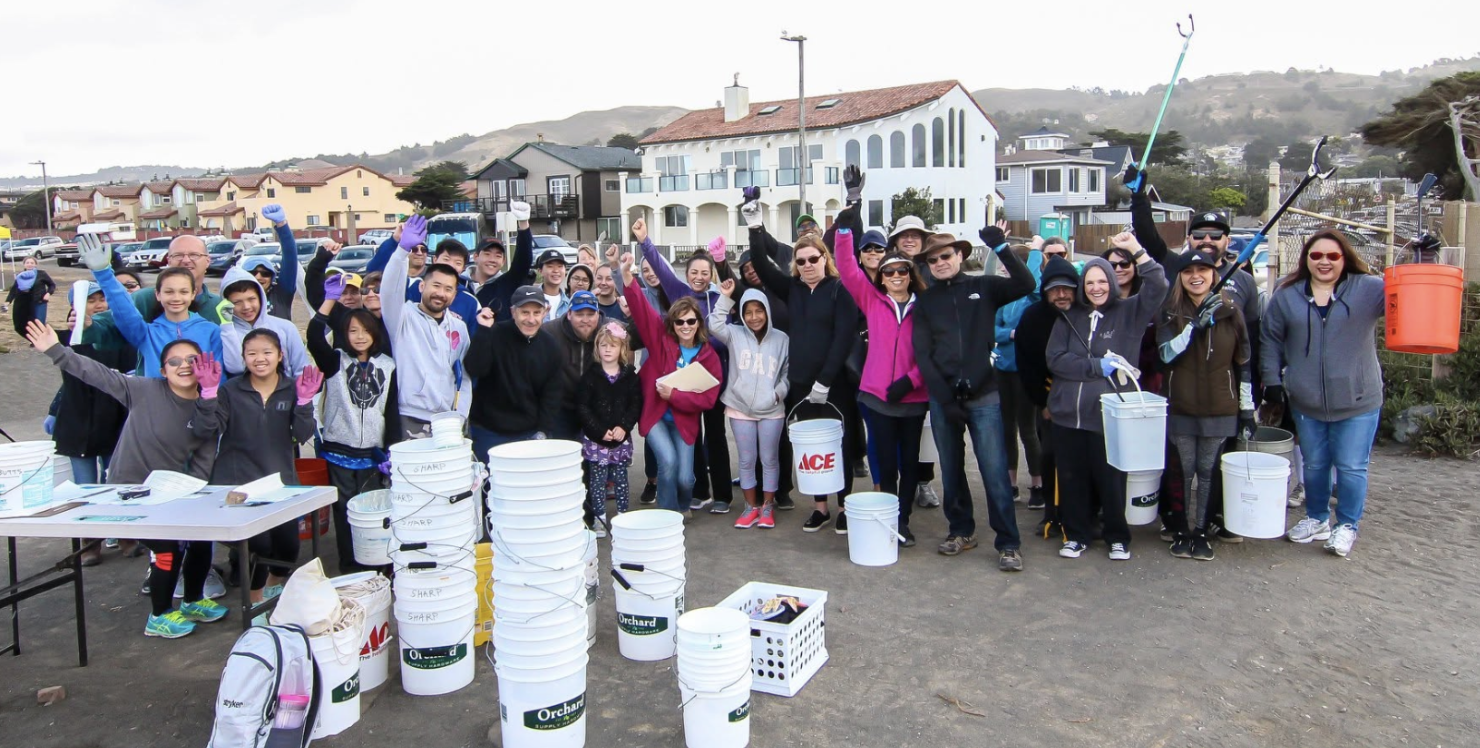 A large group of Pacifica community volunteers gathered with buckets and cleanup tools for a beach cleanup at Linda Mar Beach